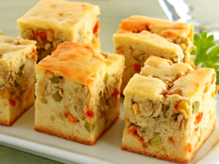 Fatia de torta de frango fit servida em prato branco com salada